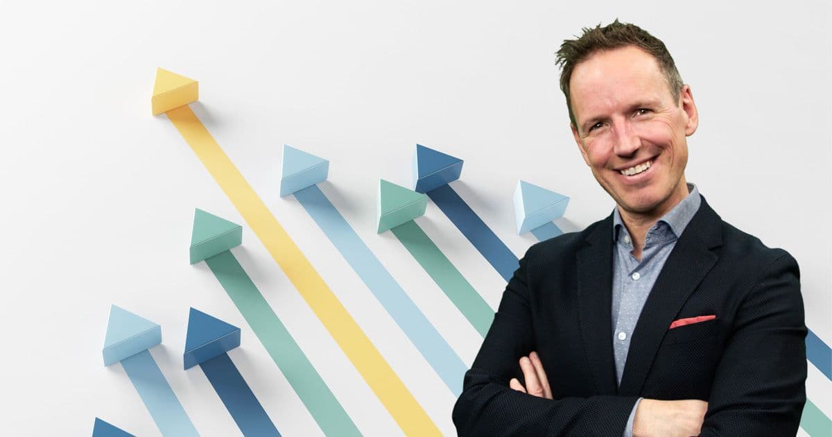 Smilende forretningsmann i dress foran illustrasjon av fargerike piler som peker oppover